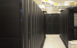 Aisle of black server racks with overhead cable trays